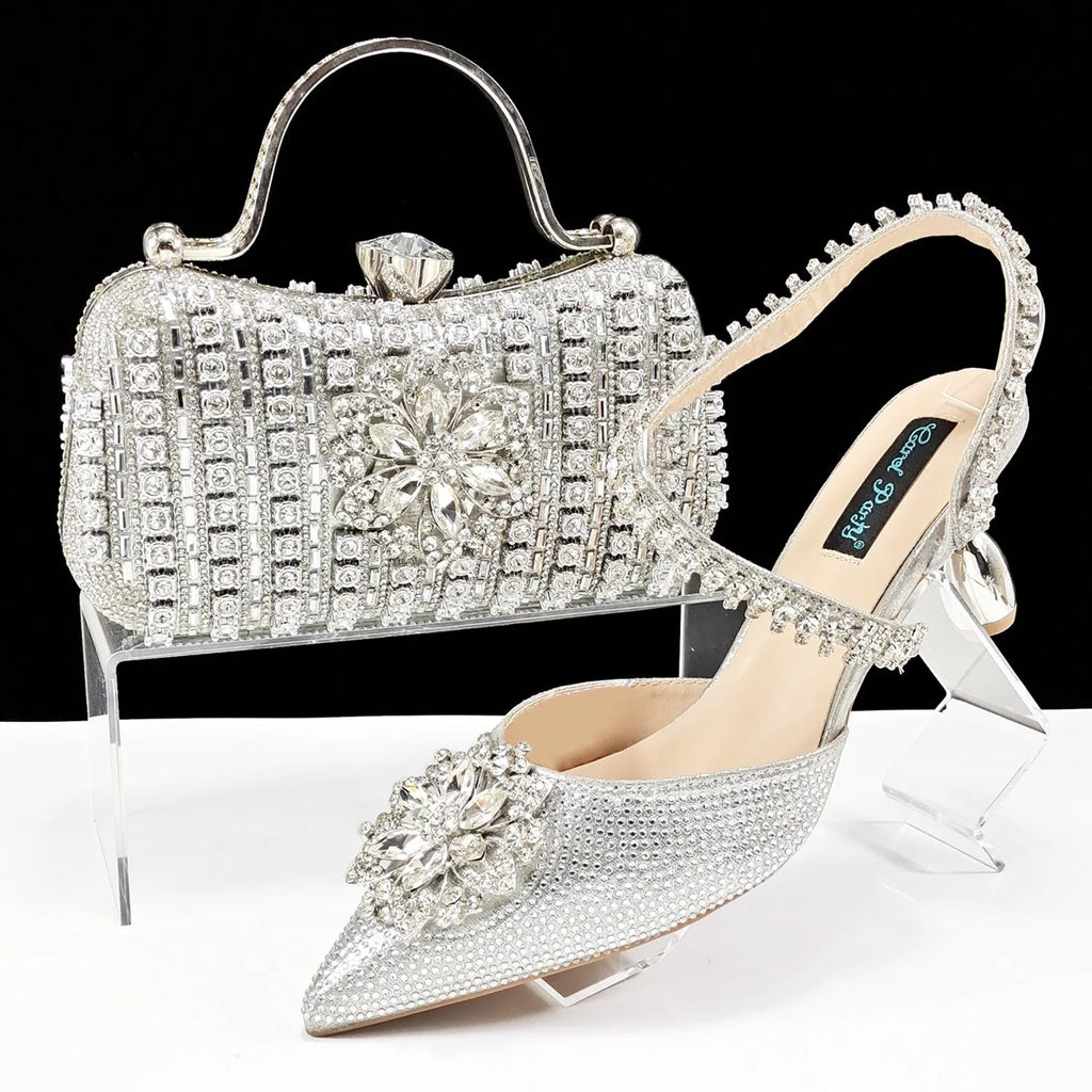 Women's black high heel shoe and matching clutch bag with floral rhinestone decoration and chain strap.