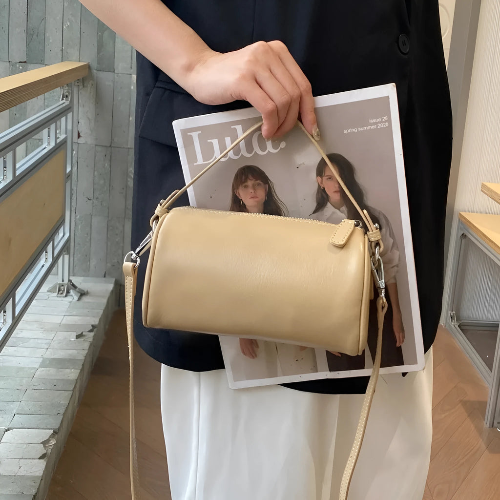 Cylindrical crossbody phone bag in soft genuine leather, shown in one of six colours including black or brown.