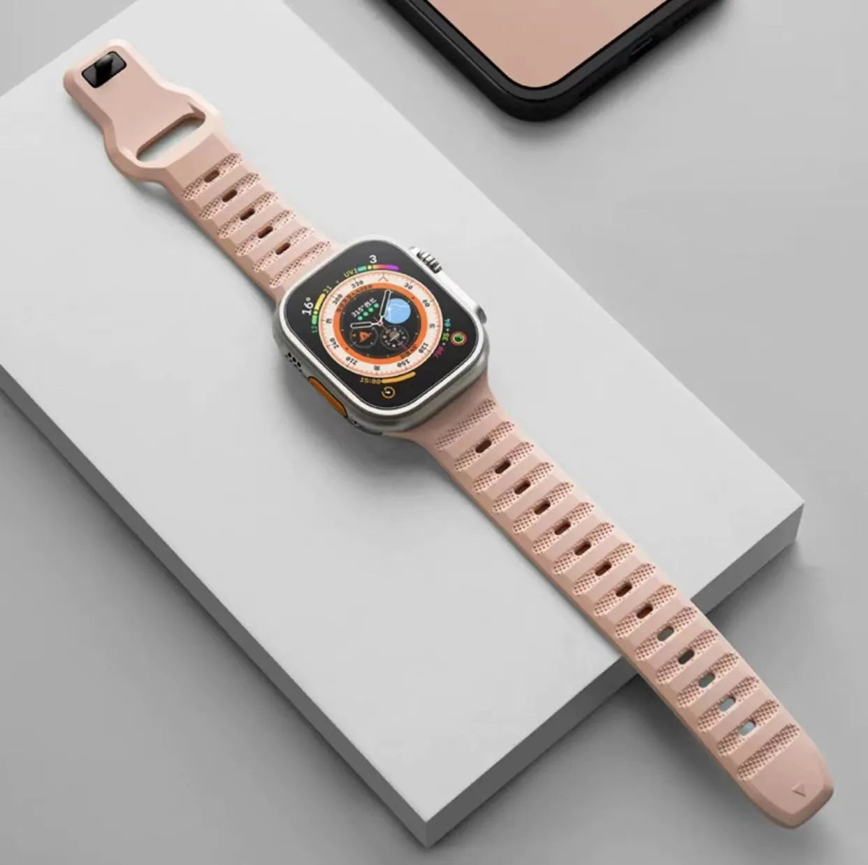 Black fluoro rubber Apple Watch strap with T-buckle closure shown detached from watch.