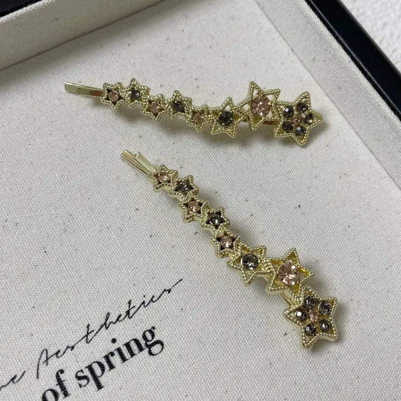 Gold-coloured alloy hair barrette with a rhinestone five-pointed star, shown as a side clip.