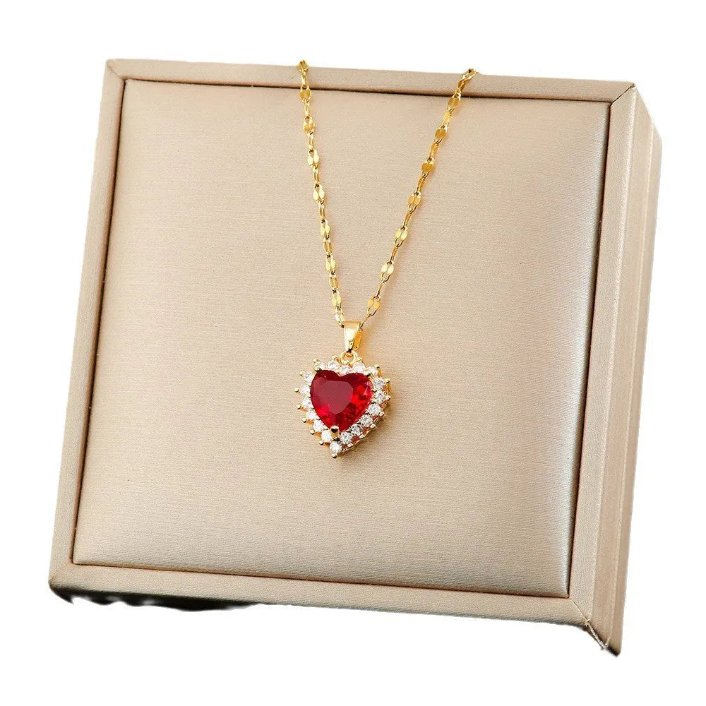 Gold-red heart pendant necklace with gemstone inlay, matching ear studs, and ring on a titanium steel water wave chain.