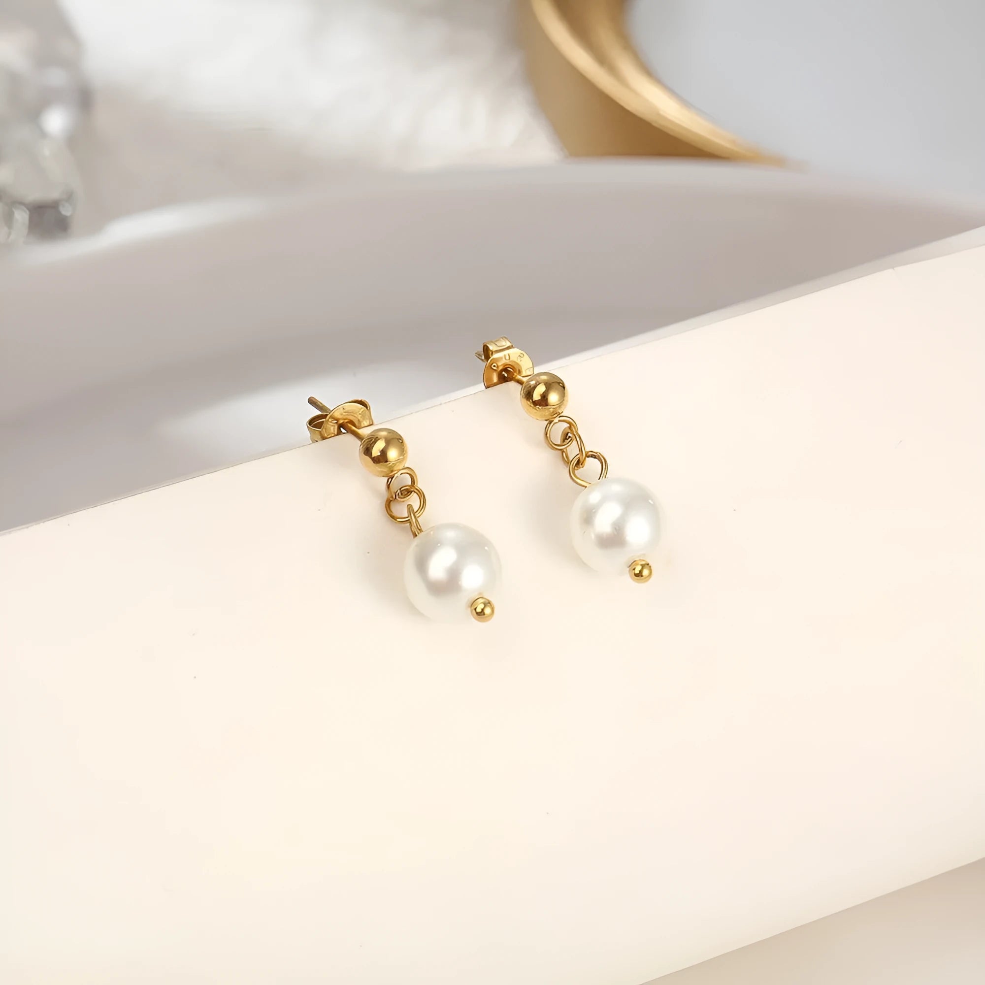 Women's gold titanium steel C-shaped earrings with pearl inlay flower design on white background