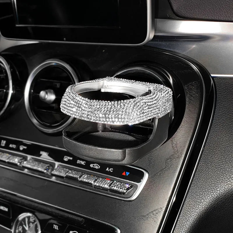 Rhinestone-encrusted white car cup holder bracket mounted on a vehicle air vent.