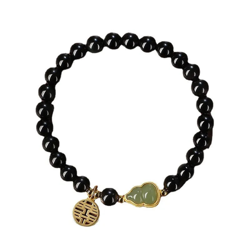 Black obsidian bracelet with a carved Hetian jade gourd charm, showing geometric beads.