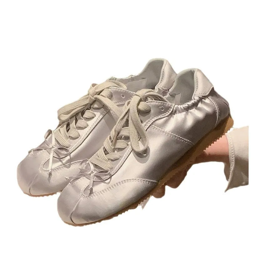 Women's satin ballet flats in champagne pink with round toe and front lace-up closure.