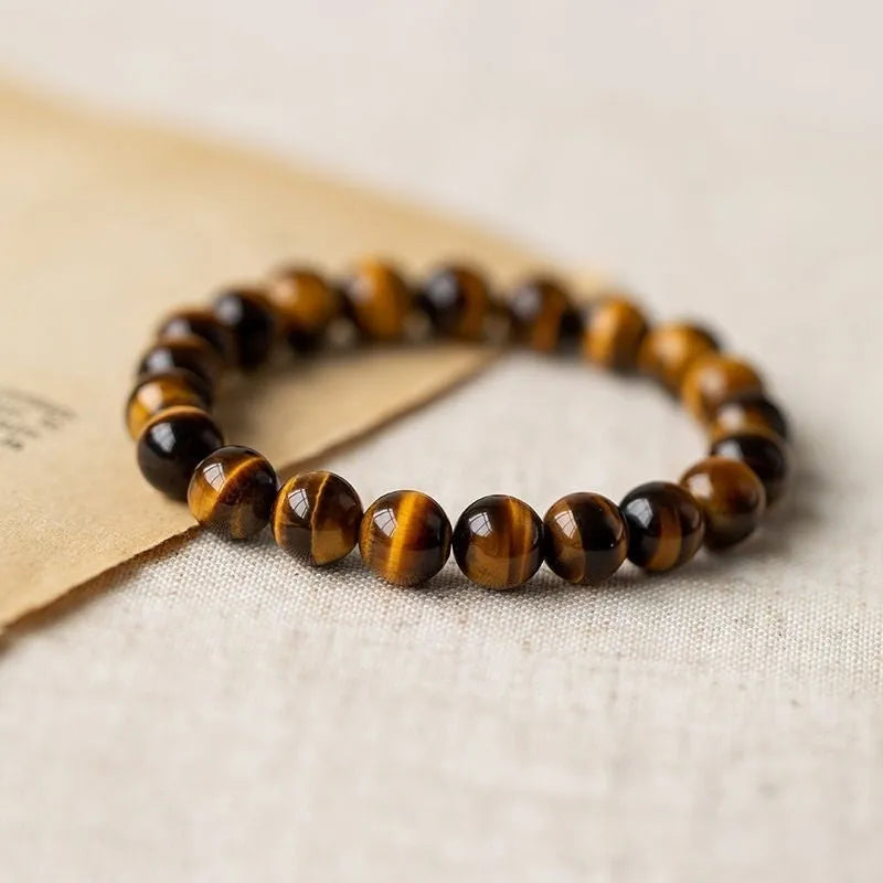 Single strand tigereye Buddha bead bracelet with dzi pattern on wrist, showing 10mm bead size.