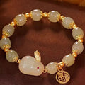 Green jade hare bracelet on wrist showing fu character and lily design details.