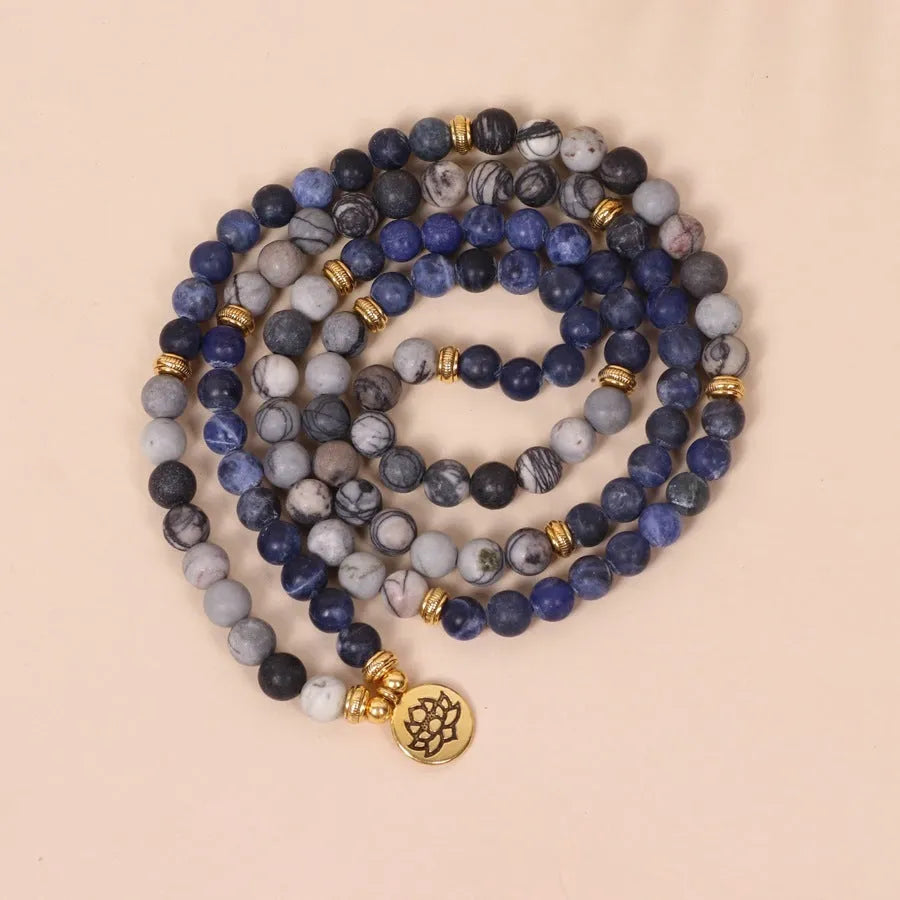 Blue multi-layer bracelet with patterned network stone beads and alloy components.