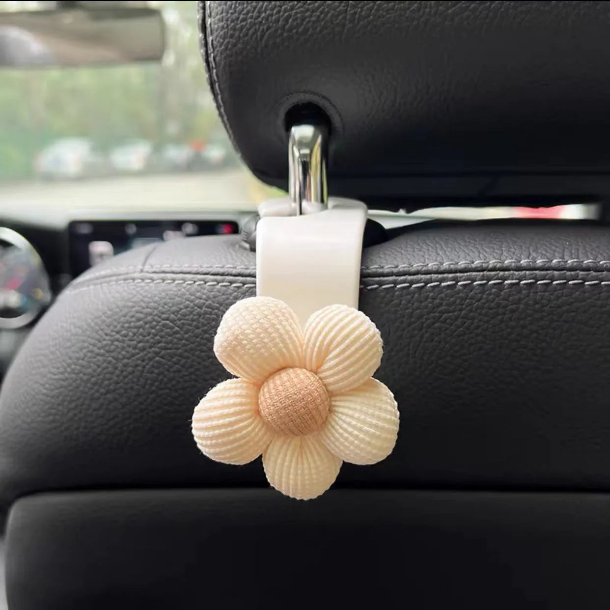 Khaki-coloured plastic car seat hook with a small decorative flower for storage.