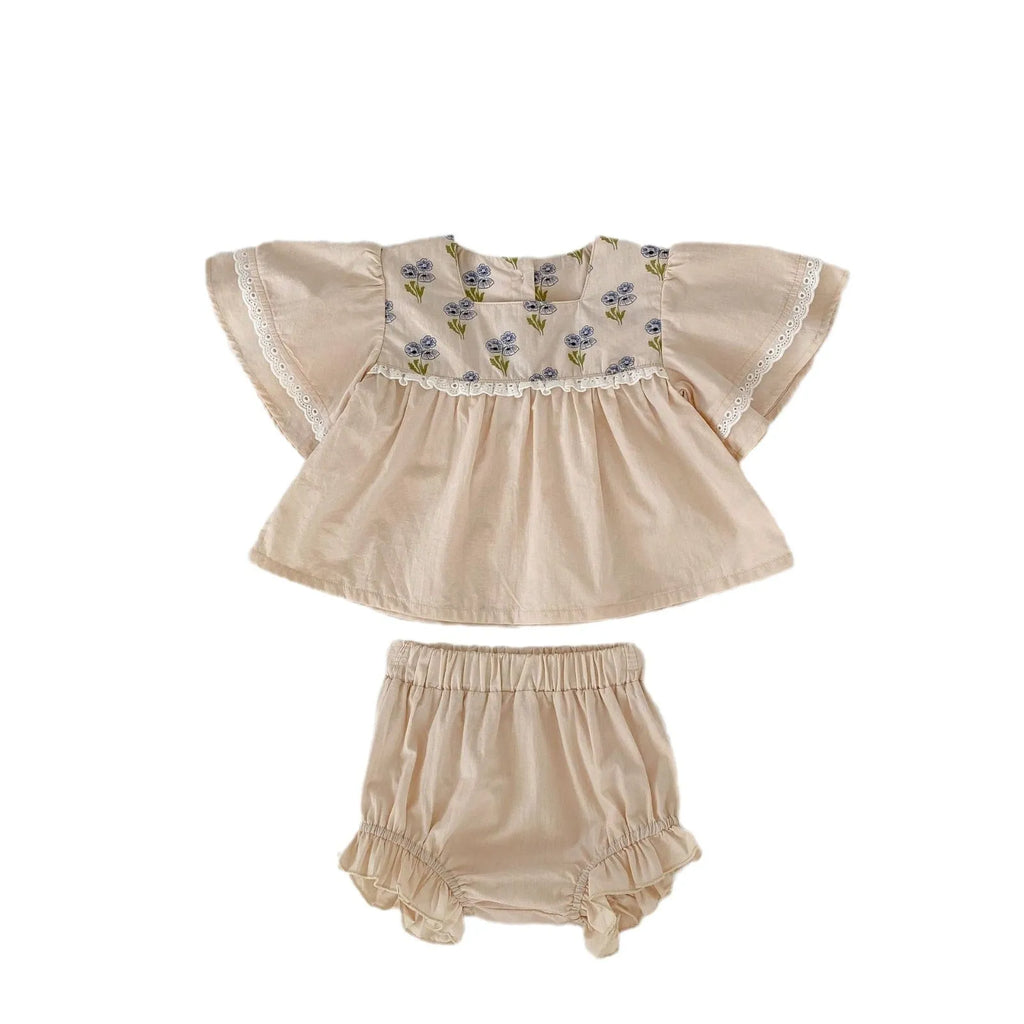 Apricot cotton two-piece suit with floral pattern, square collar top, and wooden horn buttons, next to matching bloomer pants.