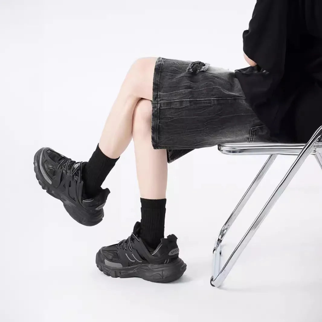 Men's washed denim shorts with ripped detailing in black or blue, showing loose retro style and fifth-pants length