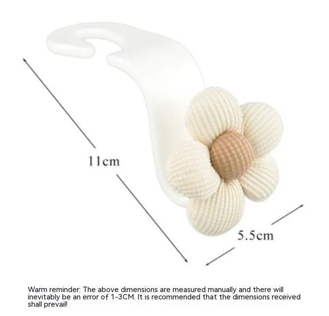 Khaki-coloured plastic car seat hook with a small decorative flower for storage.