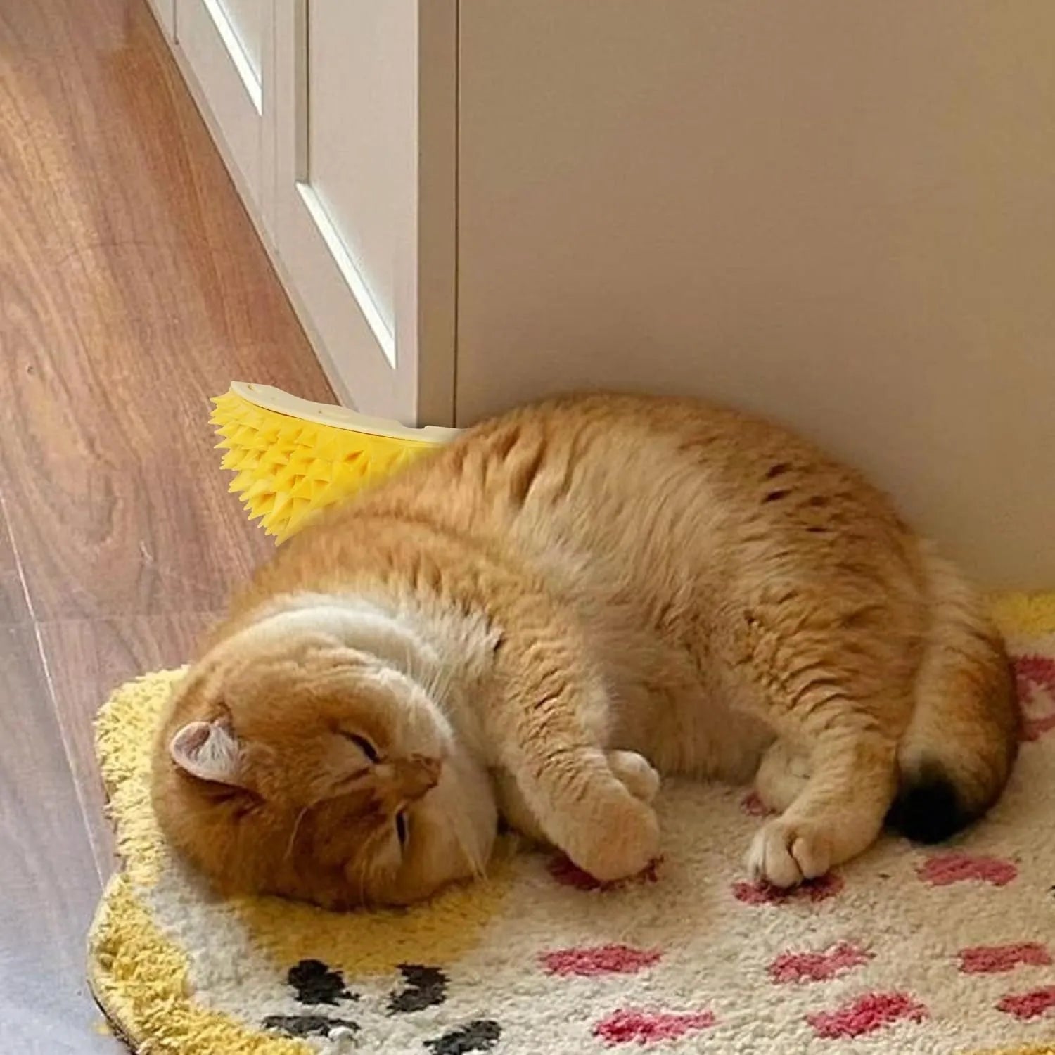 Yellow durian-shaped cat corner scratcher with grooming comb attached to a wall.