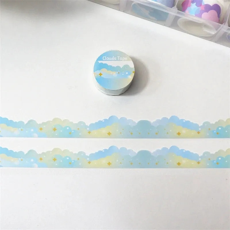 Roll of decorative washi tape with white stars and clouds pattern on a light blue background.