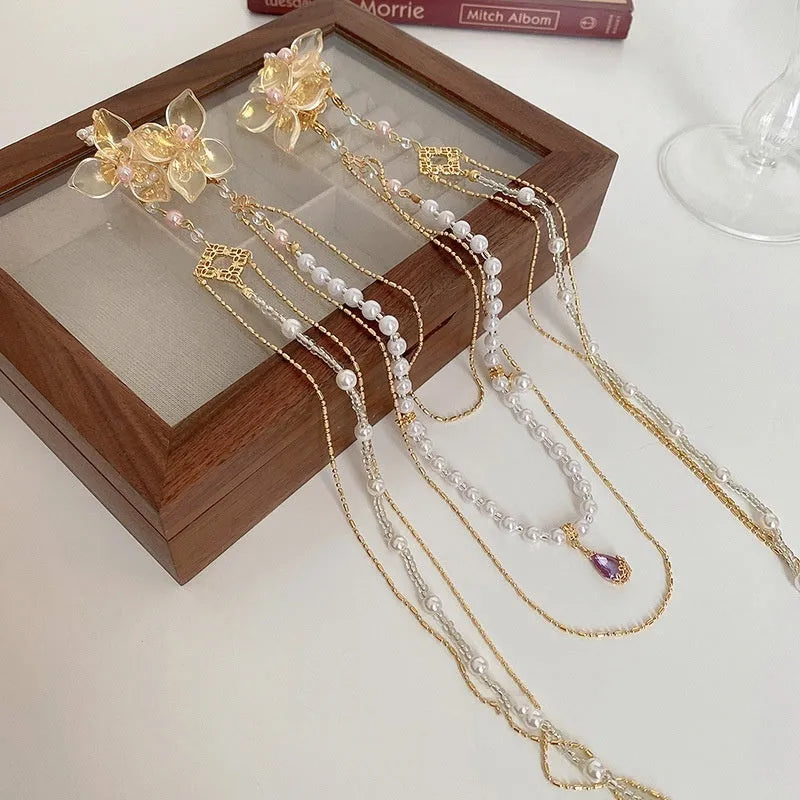 Women's gold pearl diamond flower long tassel hairpin on white background