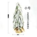 Small 24-inch white artificial Christmas tree with lights and snow spray on a desktop