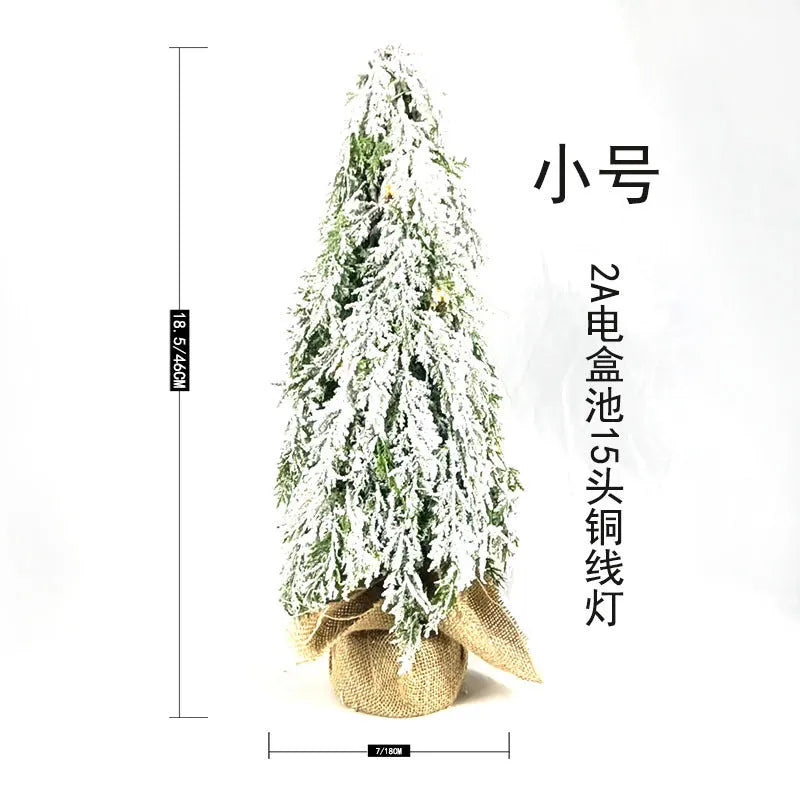 Small 24-inch white artificial Christmas tree with lights and snow spray on a desktop
