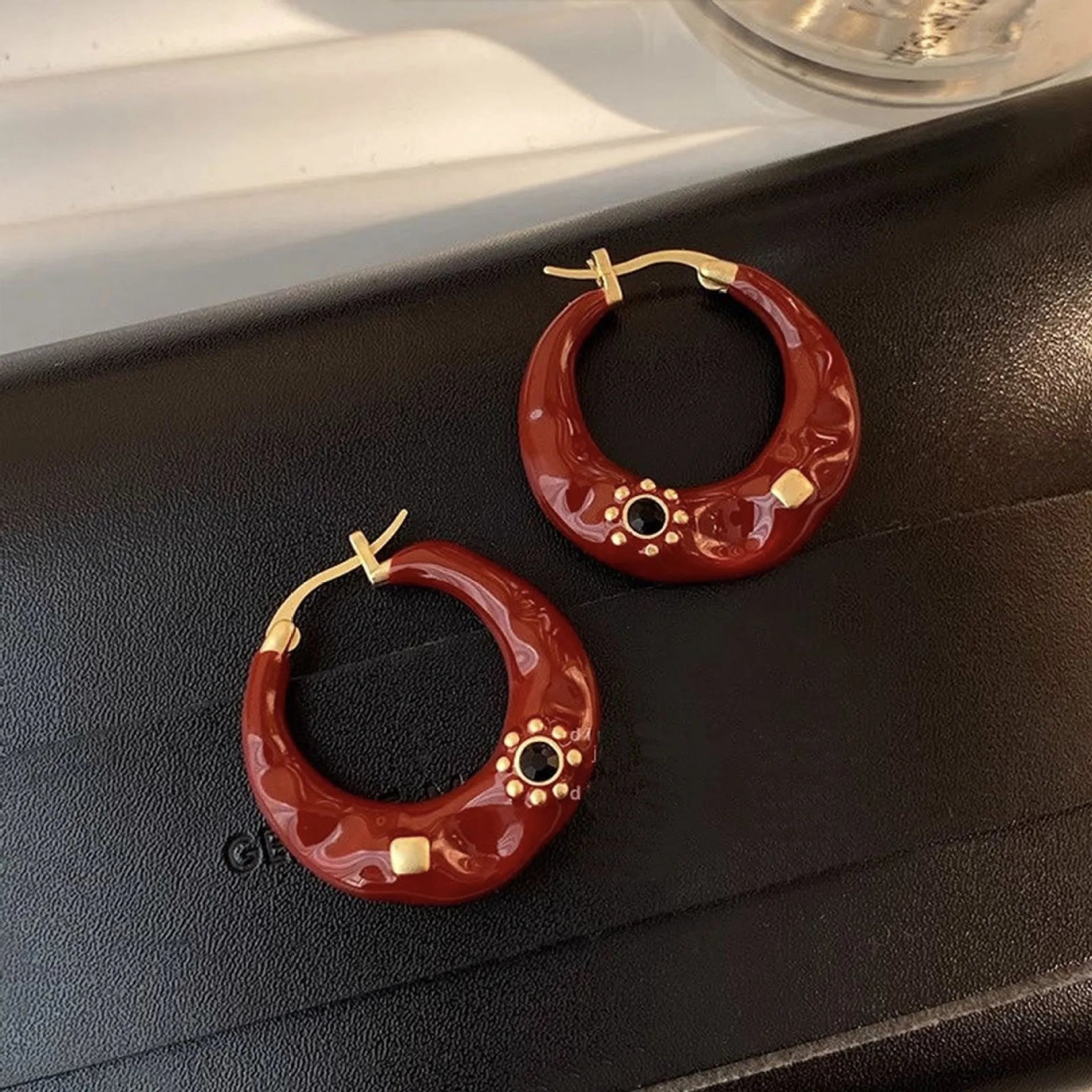 A pair of retro-style alloy ear studs with inlaid rhinestones, shown in black and red colour options.