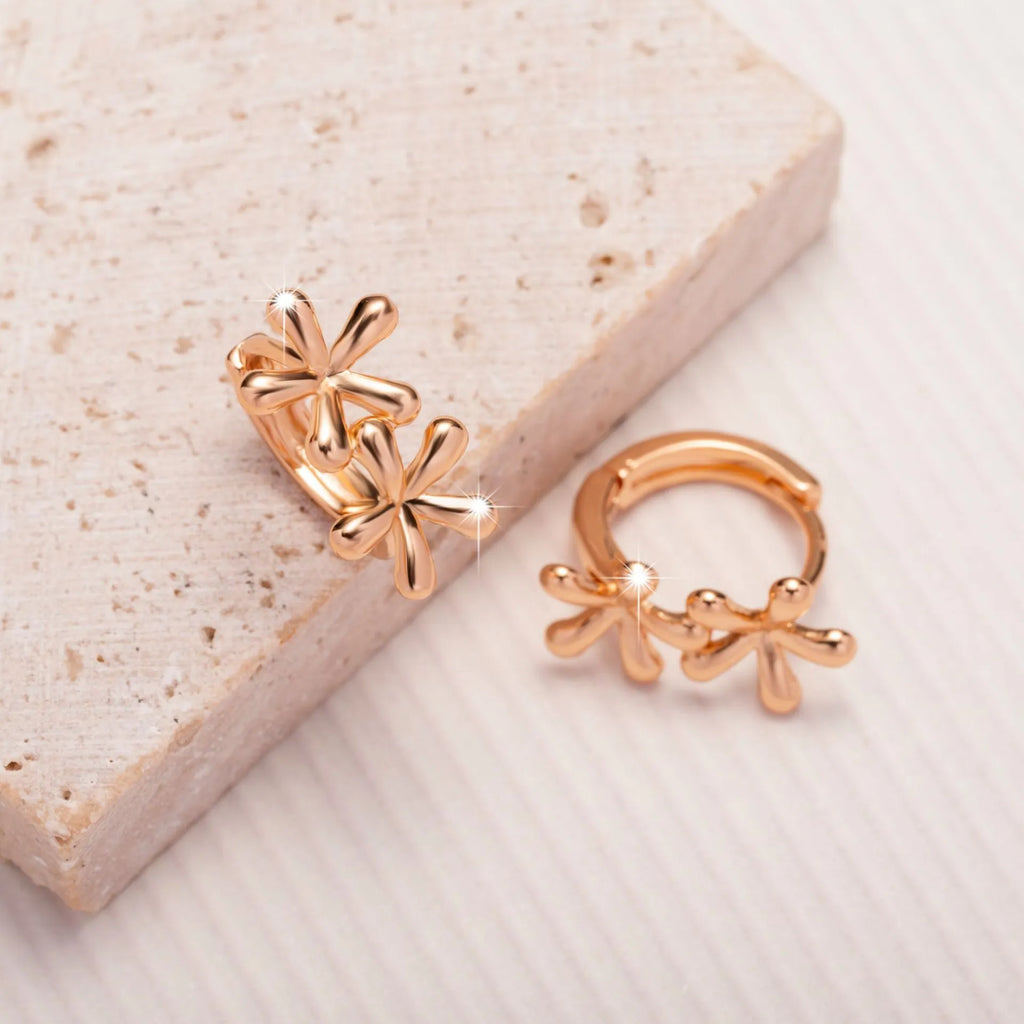 Rose gold circular earrings with a raised waterdrop floral design on a white background.