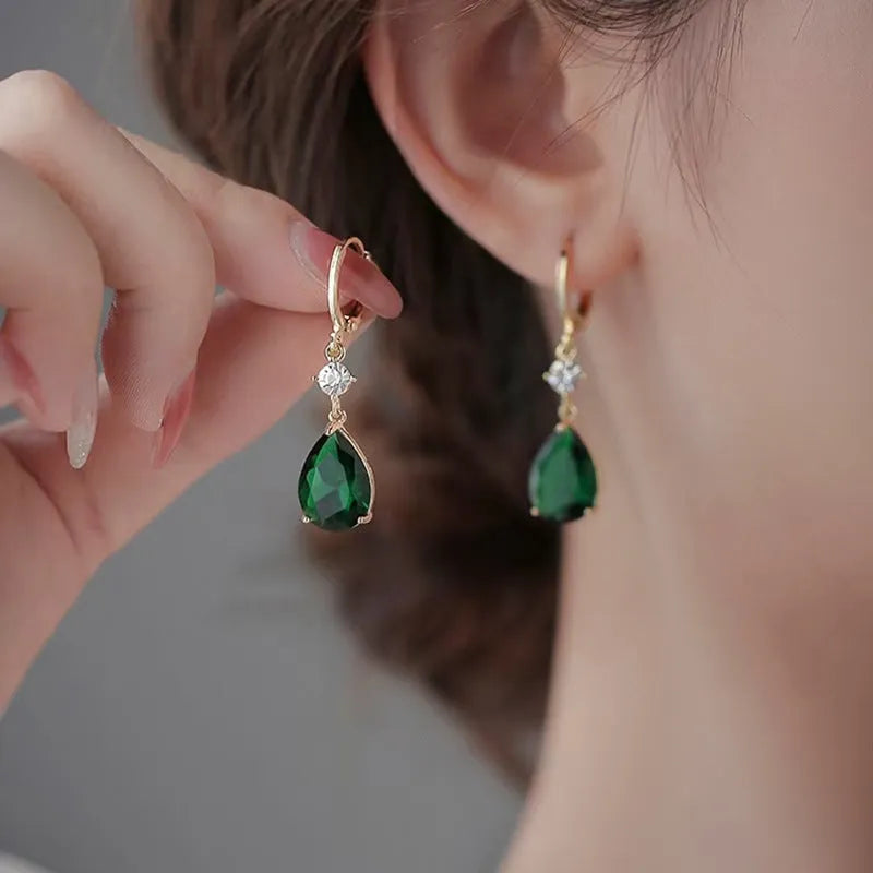 Pair of green geometric teardrop-shaped alloy earrings on a white background.