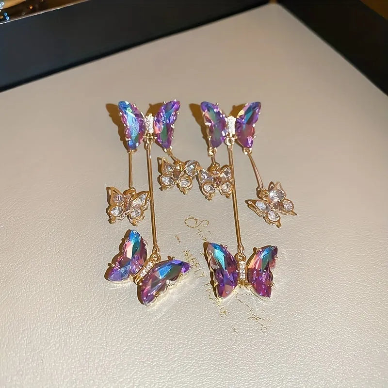 Silver Needle Blue Purple butterfly and crystal flower tassel drop earrings on a white background.