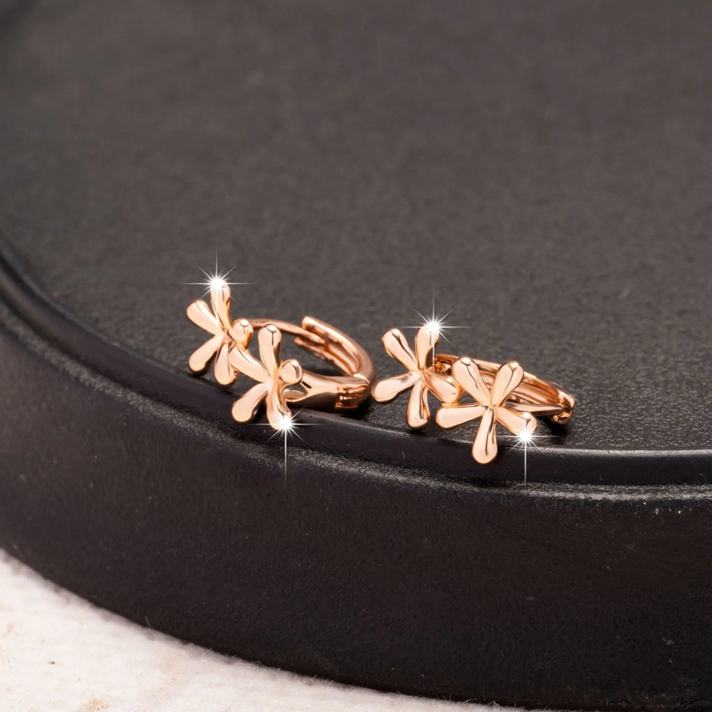 Rose gold circular earrings with a raised waterdrop floral design on a white background.
