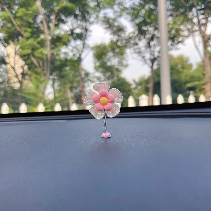 Small blue plastic swing ornament for car dashboard, 5cm tall on a grey surface.