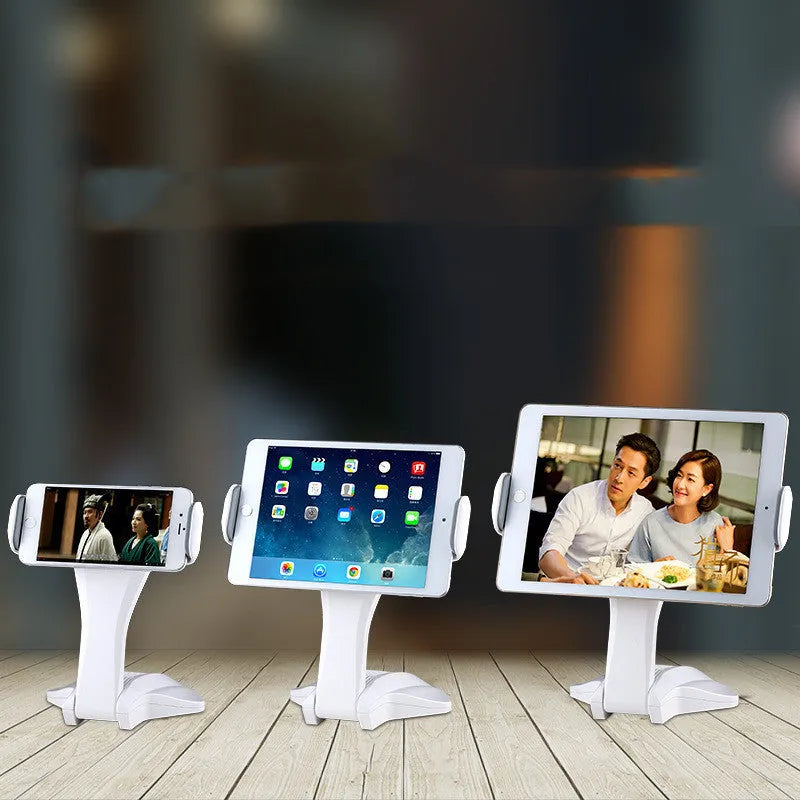 White aluminium tablet stand on a desk, showing its height and the adjustable clip for 7-15 inch devices.