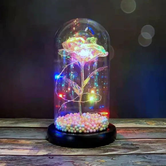 Artificial gold rose in clear glass dome on black base with LED lights for home decor