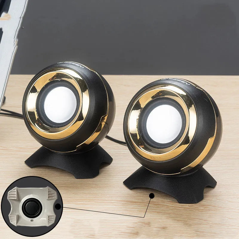 Black and gold USB-powered desktop computer speakers beside laptop showing compact 10cm dimensions