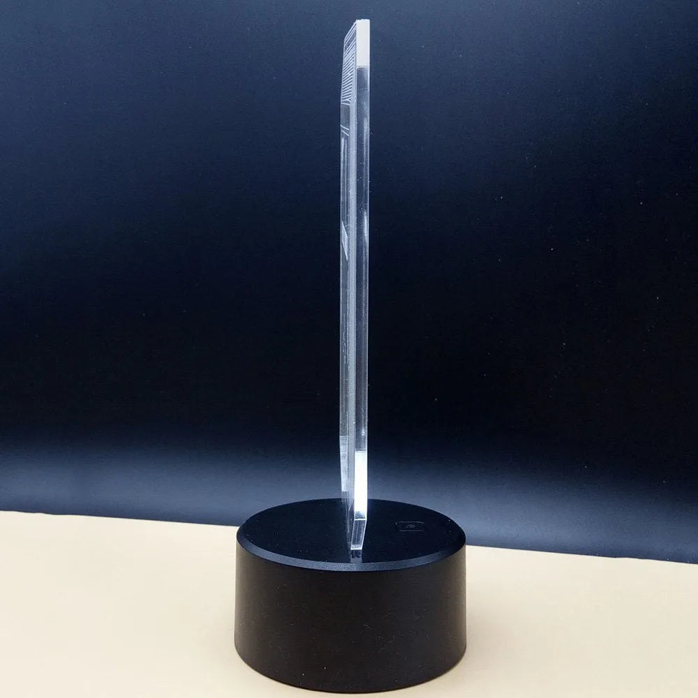 3D acrylic illusion desk lamp with colourful LED lights on a wooden desk, remote control nearby.