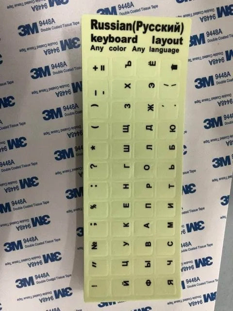 Glowing yellow multilingual keyboard stickers showing Arabic, Thai, Hebrew, French, Italian and German characters
