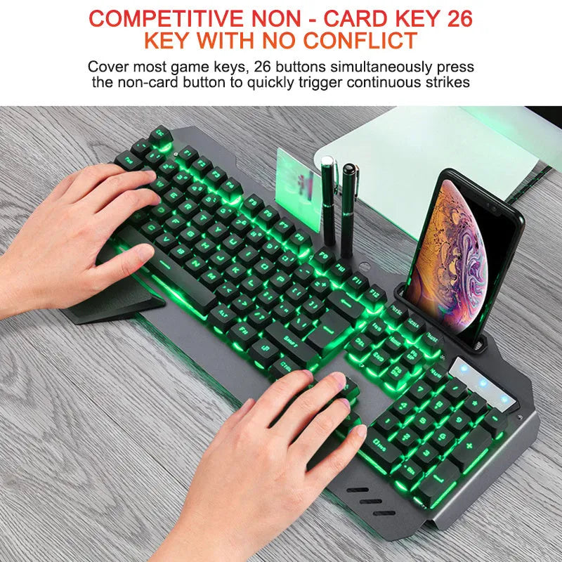 Black wired gaming keyboard with RGB backlight, phone holder, pen tray, and magnetic wrist rest on a desk