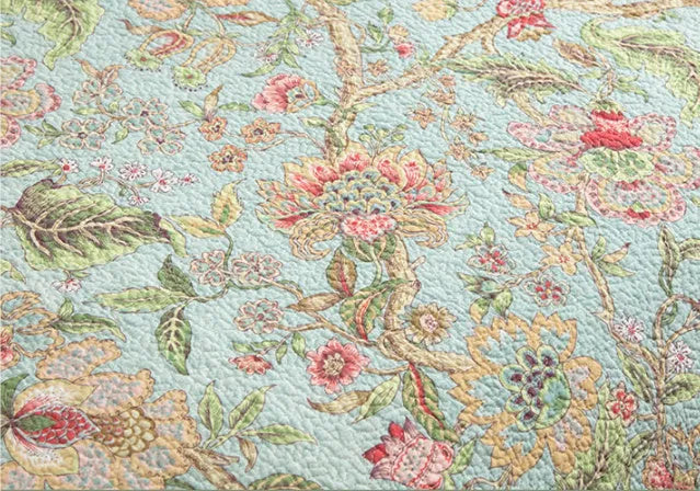 Blue American floral and bird pattern quilted cotton bedspread set on a bed