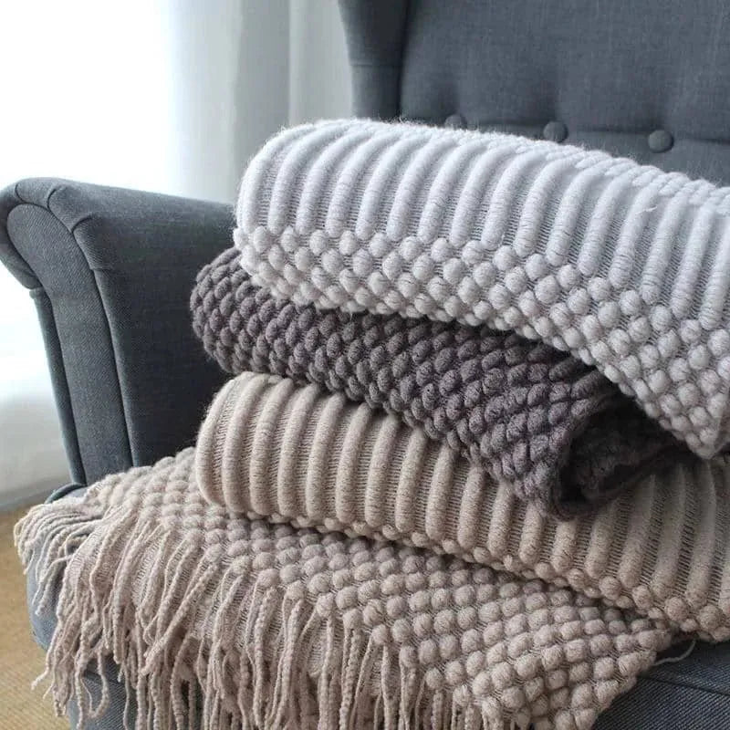 Small grey polyester nap blanket measuring 127 by 170 centimetres folded on a sofa.