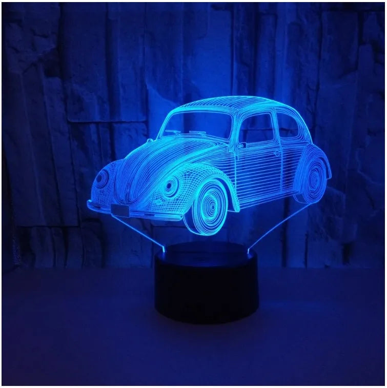 Small black 3D LED table lamp with colourful light effects and a remote control on a desk.
