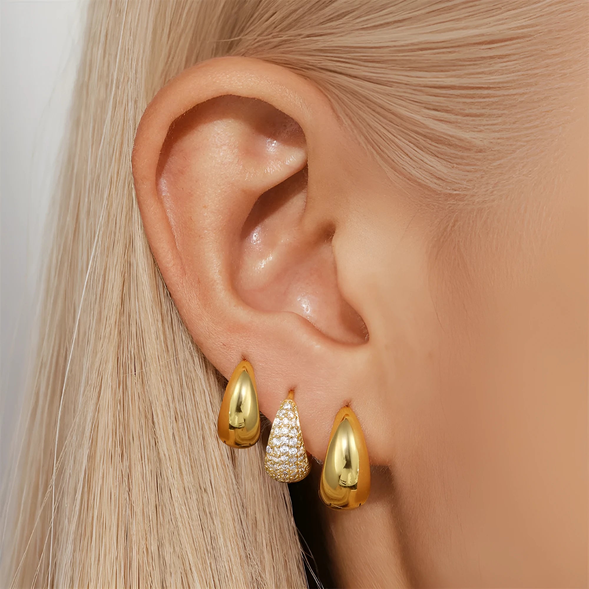 A pair of geometric brass earclip earrings with round diamond details on a gold electroplated copper base.