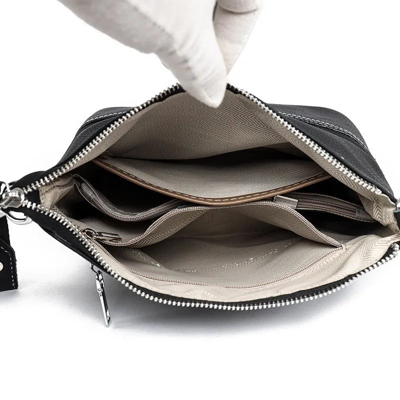 Genuine leather crossbody bag in black, horizontal square shape with splicing detail and multiple internal pockets.