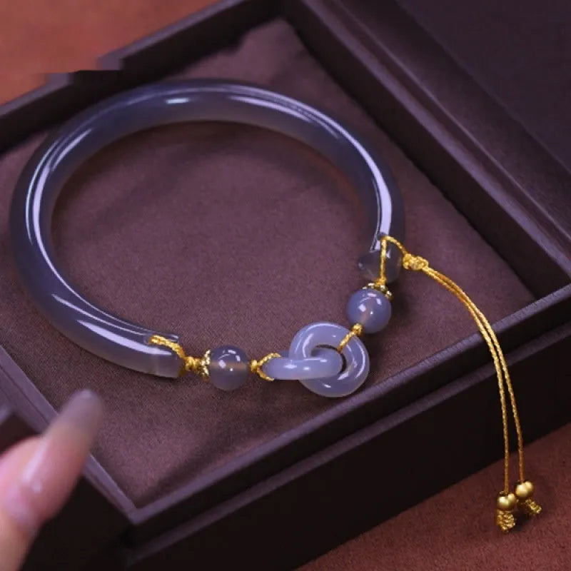 Grey smoke purple agate bead bracelet with metal ring buckle closure on a wrist.