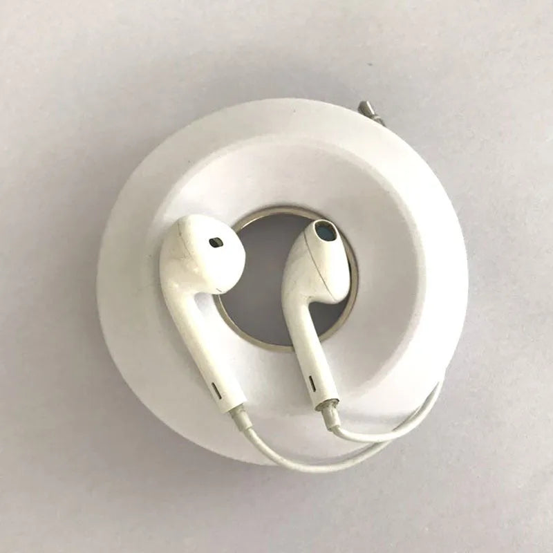 Light grey silicone donut cord reel with suction cup base and magnet for organising phone and earphone cables.