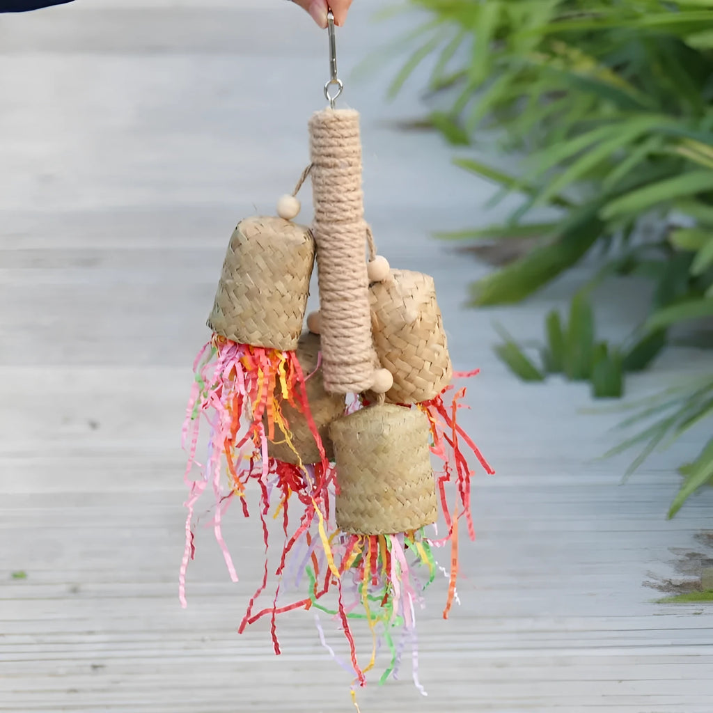 A parrot toy made of wood and sisal rope with colourful shredded paper attachments.