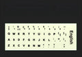 Glowing yellow multilingual keyboard stickers showing Arabic, Thai, Hebrew, French, Italian and German characters