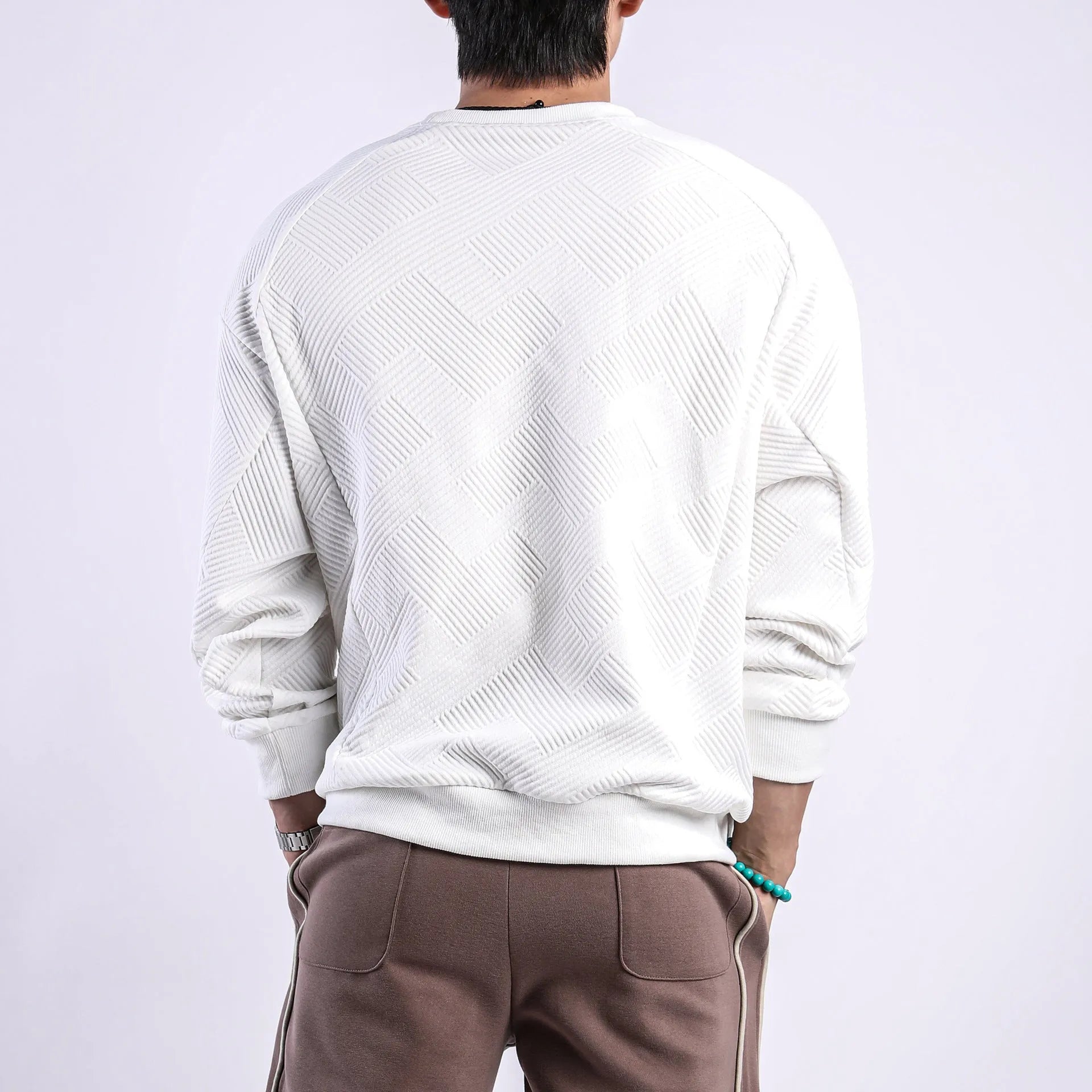Man wearing a loose-fitting army green twill jacquard long-sleeved pullover sweater.