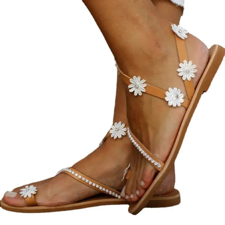 Brown ladies flat sandals with flower decoration and a rubber sole.