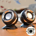 Black and gold USB-powered desktop computer speakers beside laptop showing compact 10cm dimensions
