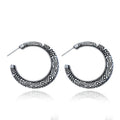 A pair of bronze C-shaped alloy earrings with a detailed vintage engraving pattern on the surface.