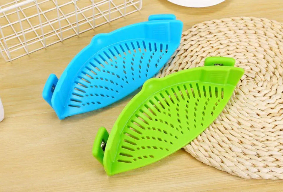 Silicone clip-on colander strainer in black with stainless steel clip attached to a pot rim for draining liquid