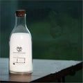 White milk bottle shaped LED nightlight on a wooden surface, USB rechargeable, with a 30-minute timer and DIY message panel