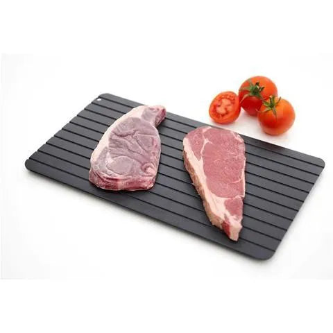 Black aluminium fast defrosting tray with silica gel feet on a kitchen countertop.