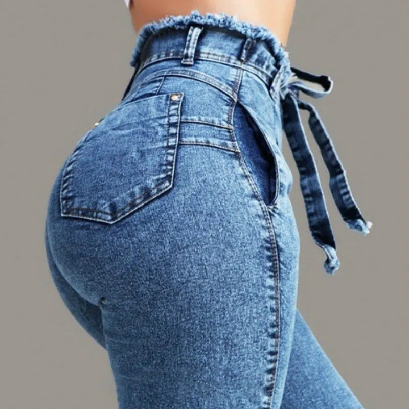 Pair of light blue fringed jeans with distressed hem detailing on a denim background.